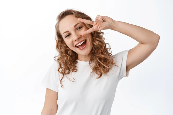 mujer joven sonriendo feliz con fondo blanco y remera corta